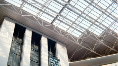 Interior bangunan modern dengan langit-langit kaca dan lift.