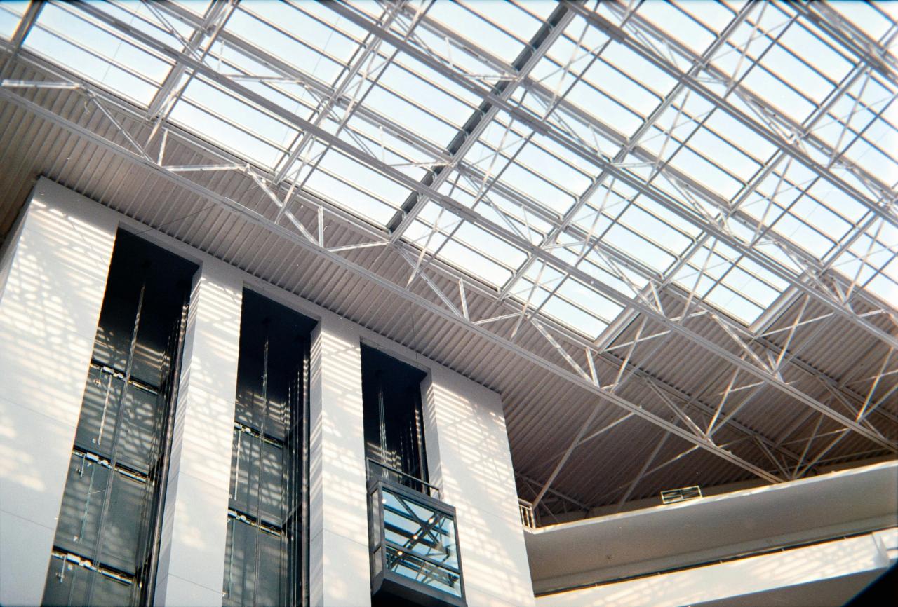 Interior bangunan modern dengan langit-langit kaca dan lift.