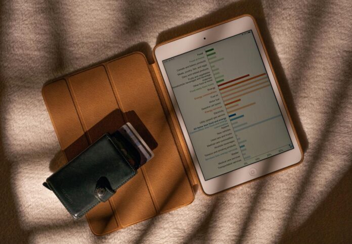 komputer tablet yang duduk di atas meja di sebelah dompet
