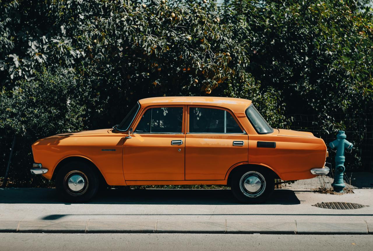 Sebuah mobil oranye diparkir di sebelah hidran pemadam kebakaran